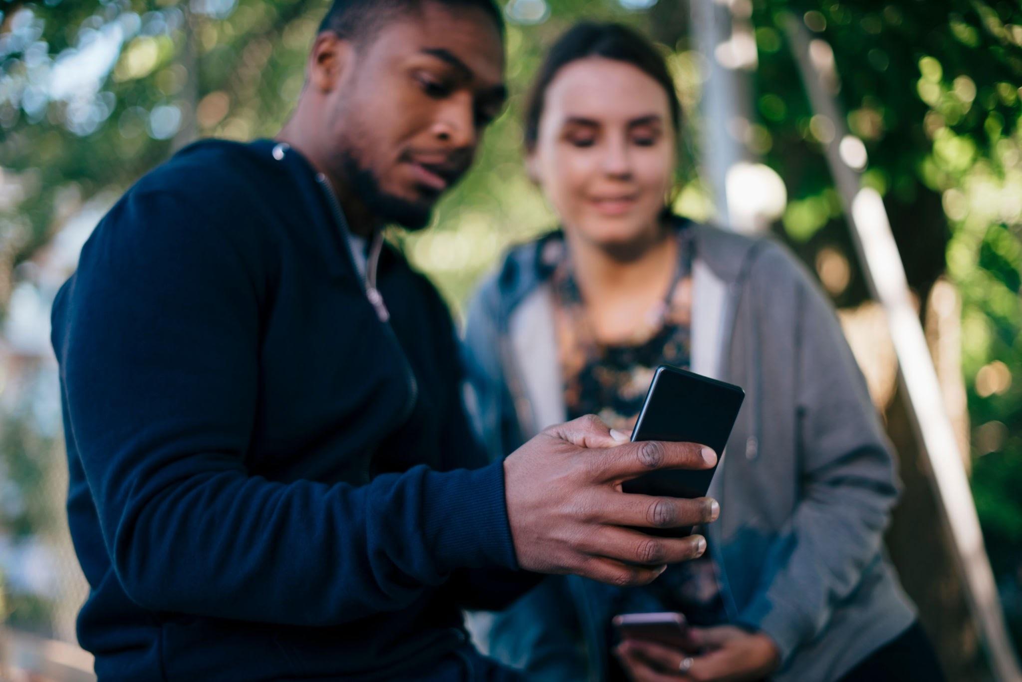 Two young adults review information together on a smartphone.